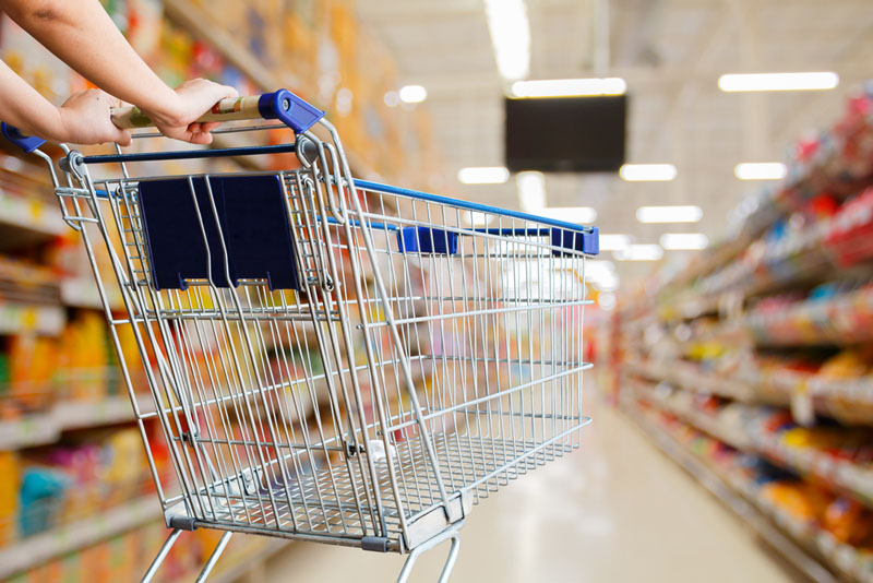 A shopper pushing a cart down a retail aisle